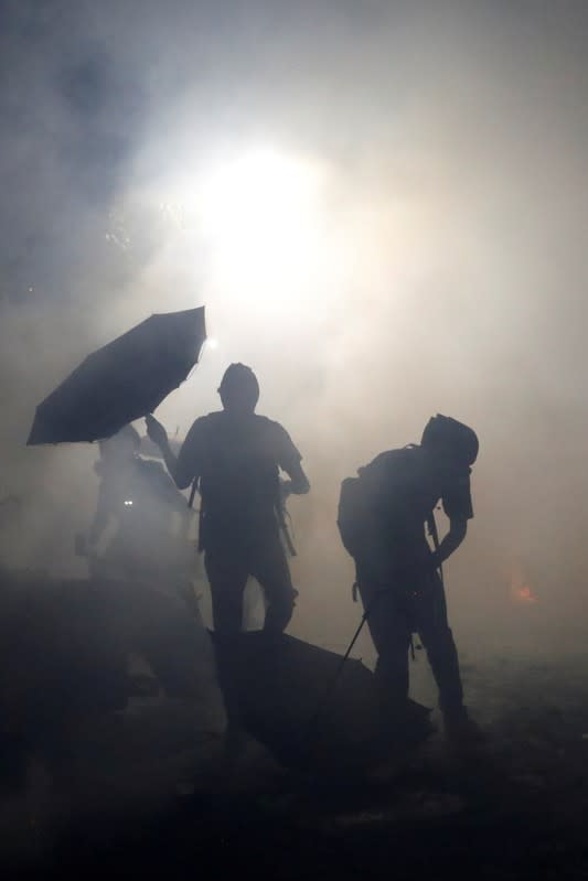 Anti-government protesters take cover during a standoff with riot police at the Chinese University of Hong Kong