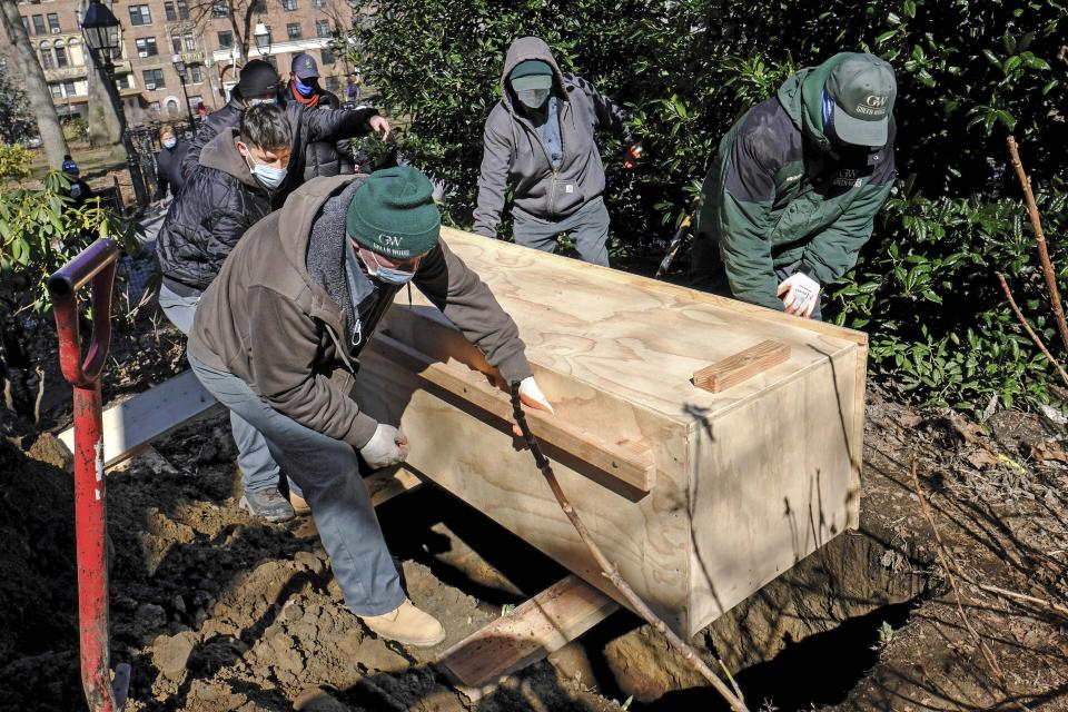 In this photo provided by the New York City Parks Department, Green-Wood Cemetery volunteers rebury the fragmentary remains of early New Yorkers found during construction in and around Washington Square Park, Tuesday, March 2, 2021, in New York. The human remains were placed in the wooden box and buried five feet below grade within a planting bed in the park, and marked with an engraved paver. (Daniel Avila/New York City Parks Department via AP)