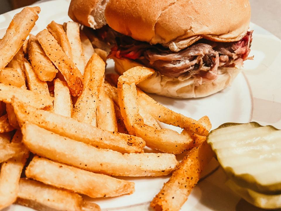 fries, a pulled pork sandwich, and pickles on a plate