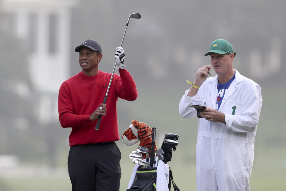 Tiger Woods prepares to hits his second shot on the first fairway with caddie Joe LaCava looking on during the final round of the Masters golf tournament Sunday, Nov. 15, 2020, in Augusta, Ga. (Curtis Compton/Atlanta Journal-Constitution via AP)