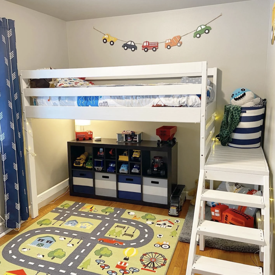 This kid's truck-themed bedroom has a road rug, a truck banner, and an array of trucks sitting on a shelf