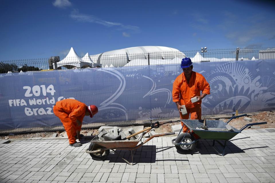 Construction workers place bricks under the midday sun next to the Dunas arena soccer stadium in Natal, June 12 , 2014. Mexico will face Cameroon in their 2014 World Cup football match here on June 13. REUTERS/Dylan Martinez