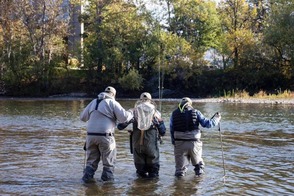 Russell Massey of Nampa, left, volunteer José Karry of Boise, center, and Richard Seltzer of Caldwell, right, carefully walk into the Boise River together during a day retreat for Idaho2Fly on Oct. 9, 2021. It was Massey and Seltzer’s first time fly fishing. Idaho2Fly is a nonprofit that helps men with cancer connect with one another through fly fishing together.