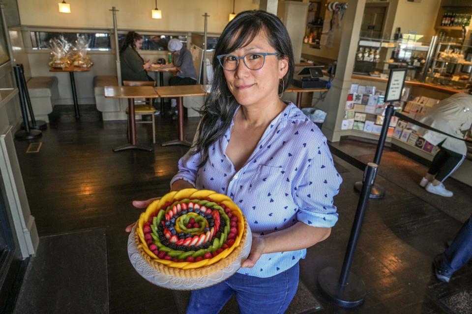 New owner Amy Foster has worked at Pastiche for 30 years. Here she holds the bakery's most popular item, the fruit tart.