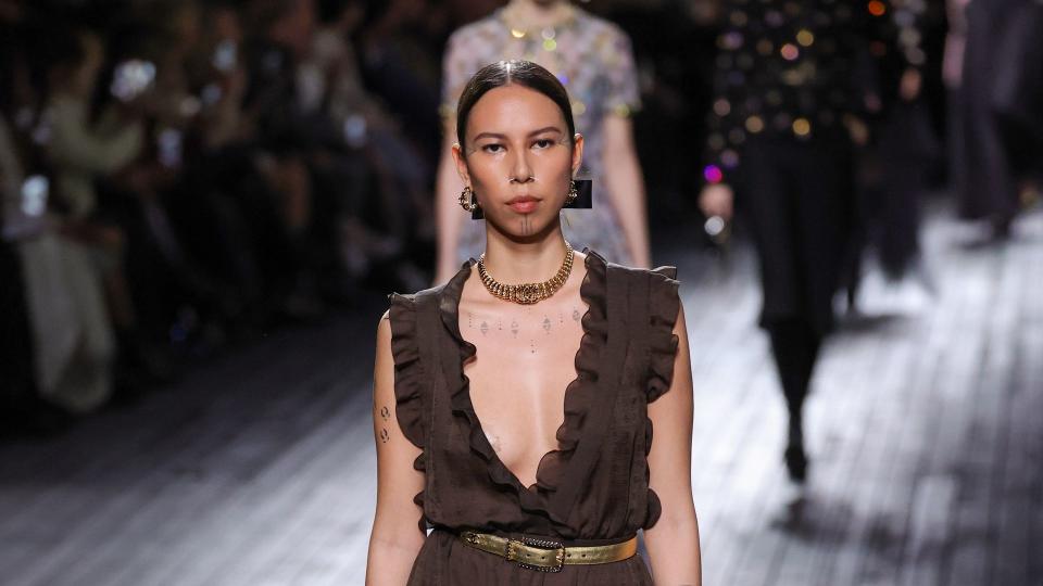 Quannah Chasinghorse walks the runway during the Chanel Womenswear Fall/Winter 2024-2025 show in a plunging neckline brown sheer gown