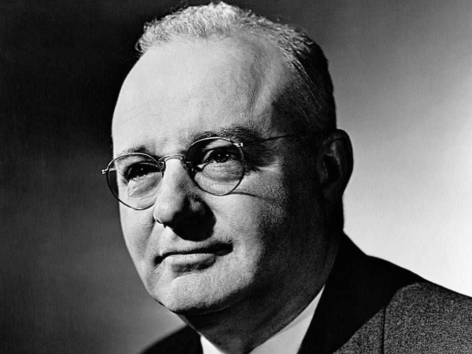 A black and white portrait of Thomas Midgley Jr. wearing a suit and tie with a pair of glasses.