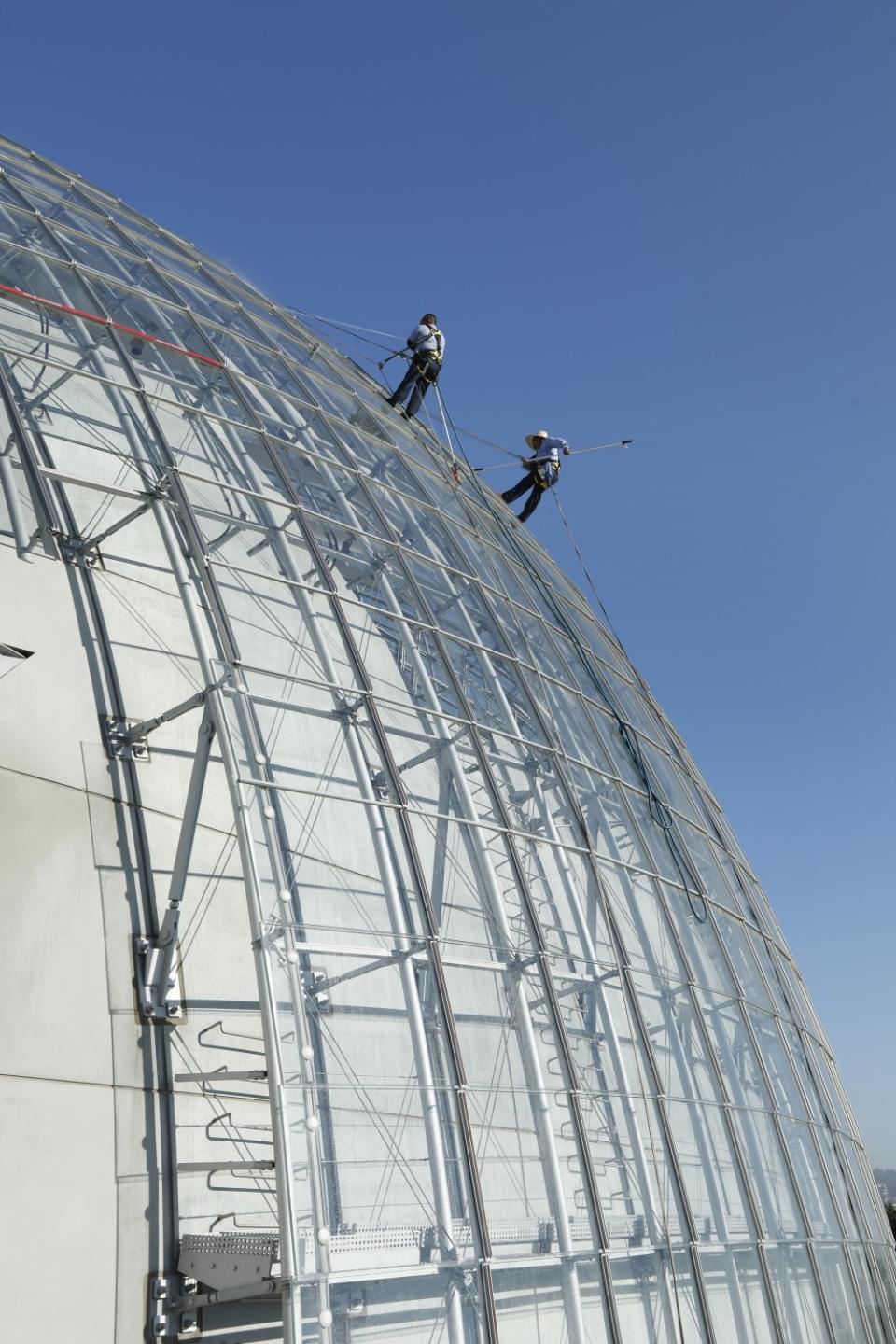 Window washers Mario Guzman, left, and Jesus Garcia clean windows of the Academy Museum of Motion Pictures Aug. 27, 2021