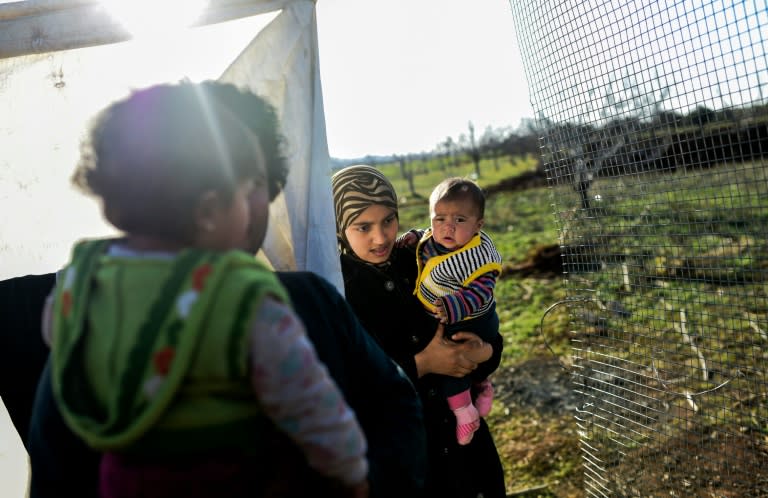 A Syrian woman living in a makeshift camp holds her baby near the Oncupinar crossing gate on February 9, 2016, in Kilis