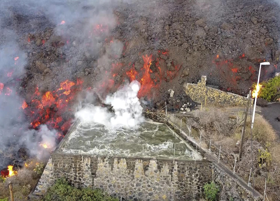 Hot lava reaches a balsa normally used for for irrigation after an eruption of a volcano on the island of La Palma in the Canaries, Spain, Monday Sept. 20, 2021. Giant rivers of lava are tumbling slowly but relentlessly toward the sea after a volcano erupted on a Spanish island off northwest Africa. The lava is destroying everything in its path but prompt evacuations helped avoid casualties after Sunday's eruption. (Europa Press via AP)