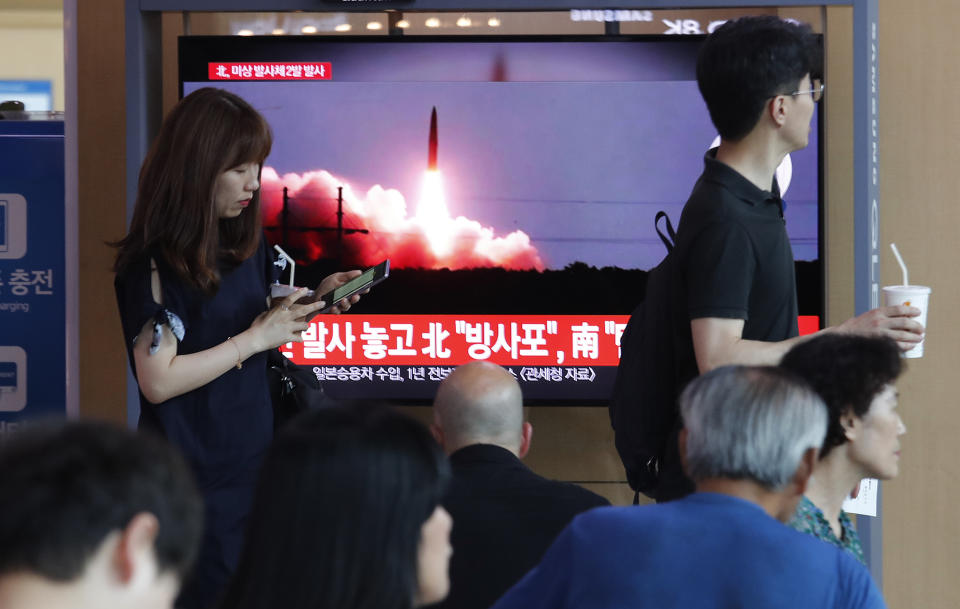 People watch a TV showing a file image of North Korea's missile launch during a news program at the Seoul Railway Station in Seoul, South Korea, Tuesday, Aug. 6, 2019. North Korea on Tuesday continued to ramp up its weapons demonstrations by firing unidentified projectiles twice into the sea while lashing out at the United States and South Korea for continuing their joint military exercises that the North says could derail fragile nuclear diplomacy. The sign reads "North Korea's multiple rocket launchers system." (AP Photo/Ahn Young-joon)