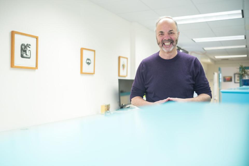 Ken Doctor stands in a fluorescent-lighted office.