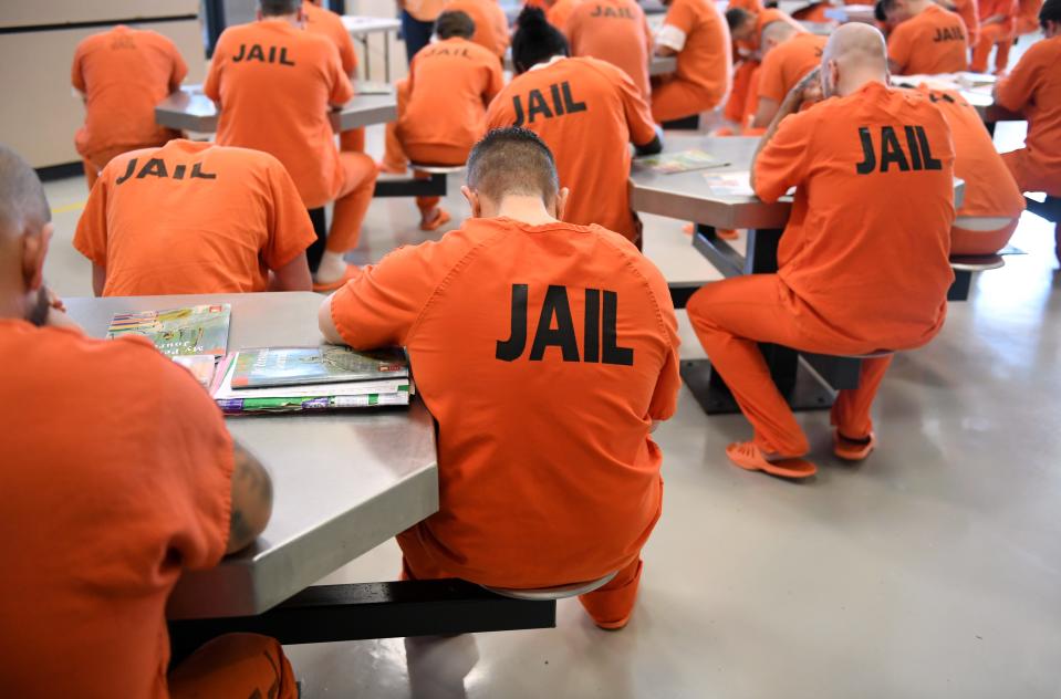 Inmates in a recovery pod at the Sarasota County jail bow their heads in prayer before a group counseling session.