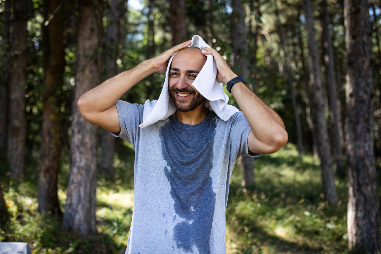 Young man wiping his sweat with a towel after training.