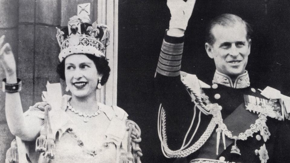 Queen Elizabeth II and Prince Phillip wave from Buckingham Palace.