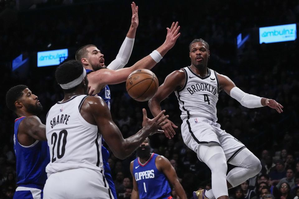 Brooklyn Nets' Dennis Smith Jr. (4) passes to teammate Day'Ron Sharpe (20) as LA Clippers' Paul George, left, and Ivica Zubac watch during the first half of an NBA basketball game Wednesday, Nov. 8, 2023, in New York. (AP Photo/Frank Franklin II)