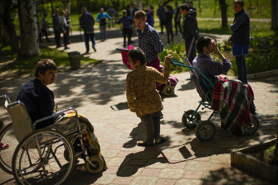 Residents spend time outdoors in a facility for people with mental and physical disabilities in the village of Tavriiske, Ukraine, Wednesday, May 11, 2022. The staff is faced with the dilemma of evacuating the facility, and how to do it with minimum disruption to the residents, some of whom have very severe disabilities and others for whom changes in environment can be disorientating and highly stressful. (AP Photo/Francisco Seco)