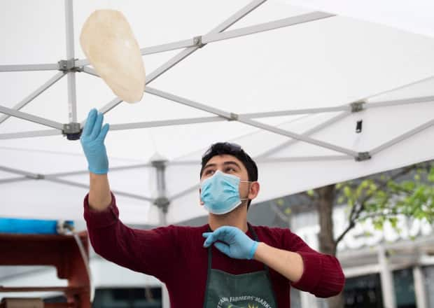 The Falafel Guys' Ahmed Altaouil tosses saj bread at the Ottawa Farmers' Market at Lansdowne Park in May 2020. These markets are open this month with COVID-19 rules such as no sitting and eating takeaway food.