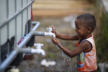 A young Rohingya migrant, who arrived recently by boat, plays with a water tap at a temporary shelter in Kuala Langsa, in Indonesia's Aceh Province May 25, 2015. REUTERS/Nyimas Laula