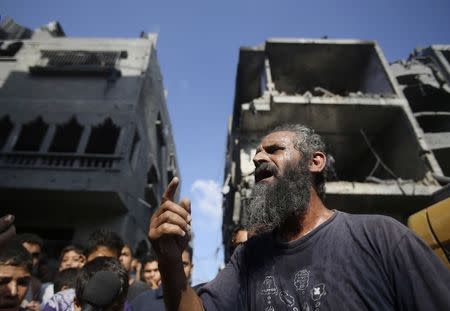 A Palestinian man reacts as rescue workers search for victims under the rubble of a house, which witnesses said was destroyed in an Israeli air strike that killed three senior Hamas military commanders, in Rafah in the southern Gaza Strip August 21, 2014. REUTERS/Ibraheem Abu Mustafa