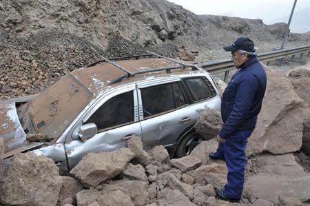 A rescue worker inspects a car caught under a landslide after an earthquake and tsunami hit the northern port of Iquique, April 2, 2014. REUTERS/Cristian Vivero