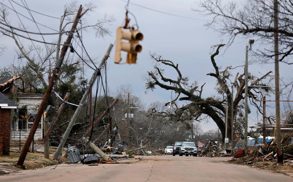 Cars carefully navigate downed trees and power lines on Chestnut Blvd. in Selma, Alab., Friday, Jan. 13, 2023, after a tornado passed through the area the day before. Rescuers raced Friday to find survivors in the aftermath of a tornado-spawning storm system that barreled across parts of Georgia and Alabama.