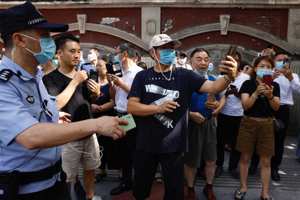 A police man urges residents taking photos outside the United States Consulate to move on in Chengdu in southwest China's Sichuan province on Sunday, July 26, 2020. China ordered the United States on Friday to close its consulate in the western city of Chengdu, ratcheting up a diplomatic conflict at a time when relations have sunk to their lowest level in decades. (AP Photo/Ng Han Guan)