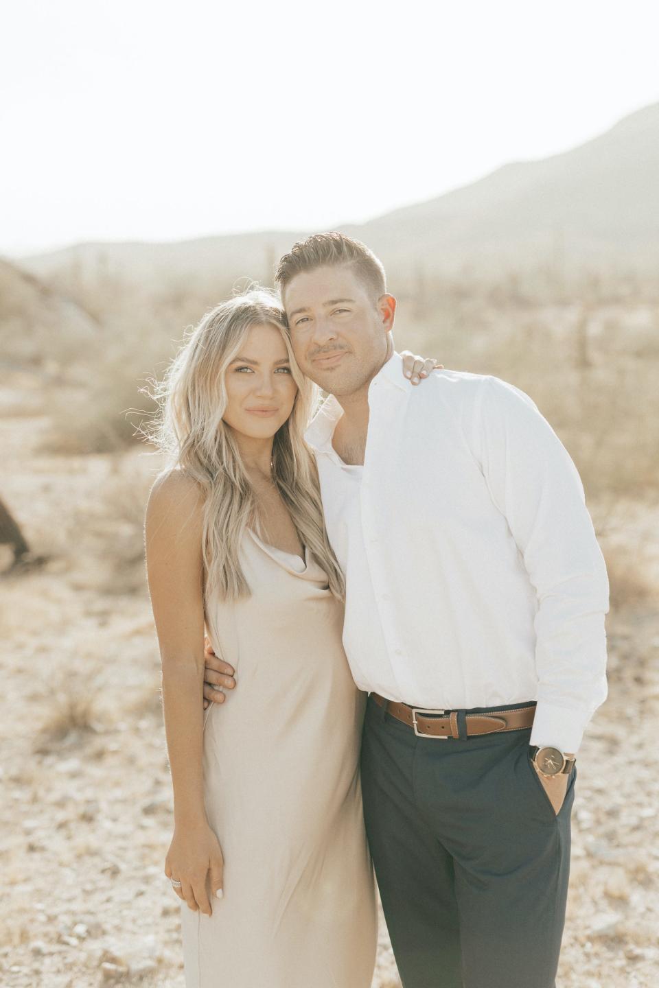 A man and woman lean together in a desert.