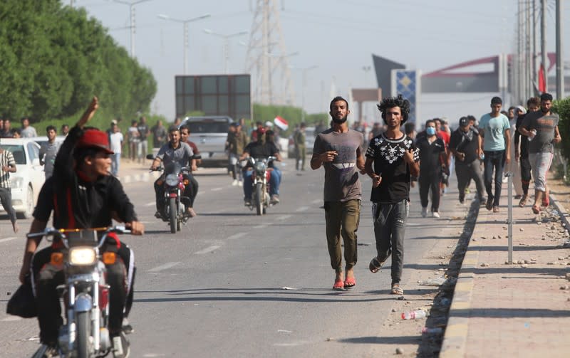 Iraqi demonstrators run away during clashes with Iraqi army forces, guard at the entrance of Umm Qasr Port during ongoing anti-government protests, south of Basra