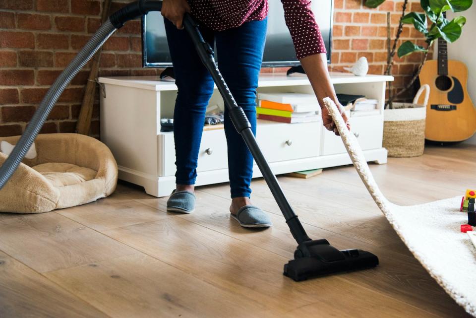 Person vacuuming under rug to get rid of crickets