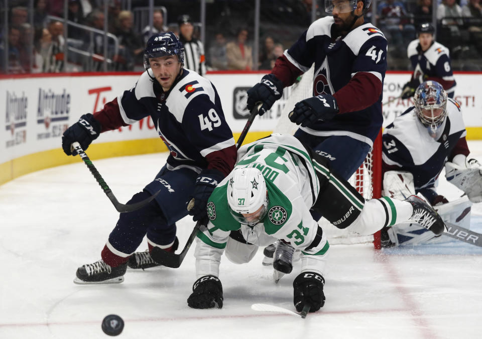 Dallas Stars center Justin Dowling, center, tumbles to the ice while pursuing the puck betwen Colorado Avalanche defenseman Samuel Girard, left, and center Pierre-Edouard Bellemare in the second period of an NHL hockey game Tuesday, Jan. 14, 2020, in Denver. (AP Photo/David Zalubowski)