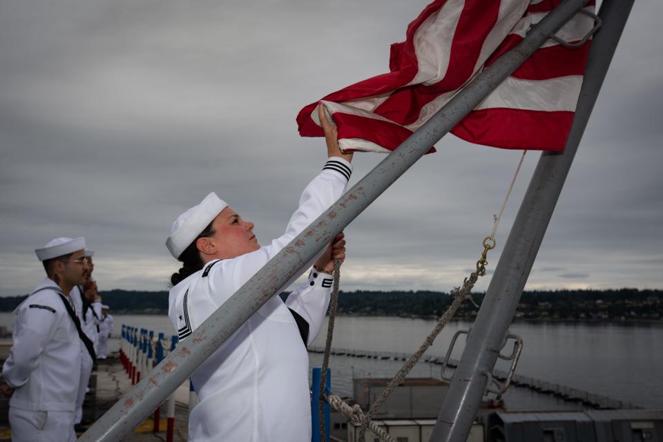 Alyssa Rogers, Aviation Boatswain's Mate (Aircraft Handling), Somersworth, NH, raises the national flag aboard the flight deck of the Nimitz-class aircraft carrier USS Ronald Reagan (CVN 76) at Naval Base Kitsap in Bremerton, Washington, on Aug. 13, 2024.