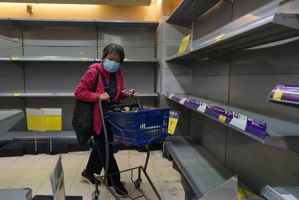 A woman wearing face mask walks past empty shelf of tissue papers at a supermarket in Hong Kong, Thursday, Feb. 6, 2020. Ten more people were sickened with a new virus aboard one of two quarantined cruise ships with some 5,400 passengers and crew aboard, health officials in Japan said Thursday, as China reported 73 more deaths and announced that the first group of patients were expected to start taking a new antiviral drug. (AP Photo/Vincent Yu)