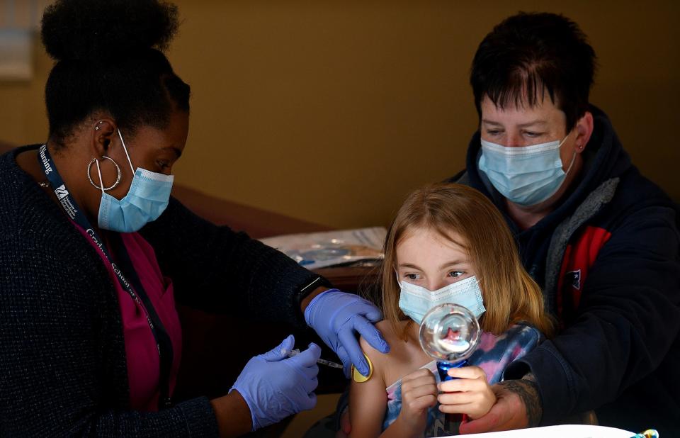 Karmen Piltzecker, 8, of Rutland holds a spinning toy meant to distract her from the COVID-19 shot in her arm as her mother Christine watches at CENTRO, Nov. 6, 2021.