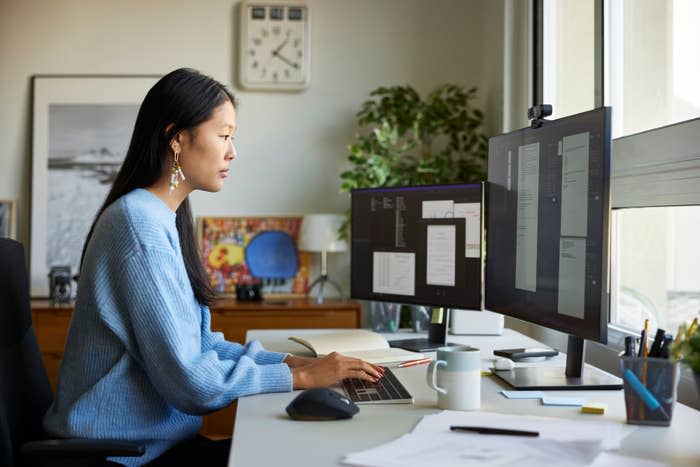 Person at a desk using a computer with multiple monitors for work