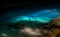 Gentle ripples visible across the crystal-clear water as the sun momentarily breaks through the entrance to one of Chapada Diamantina’s many caves.