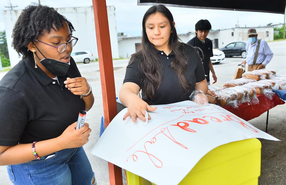 Students from Spartanburg High School sell bread at the Bellews Market in Spartanburg on June 25, 2022.  Nalani Manigault, 15, and Andrea Castellanos-Garcia, 17, work to prepare to sell products. 