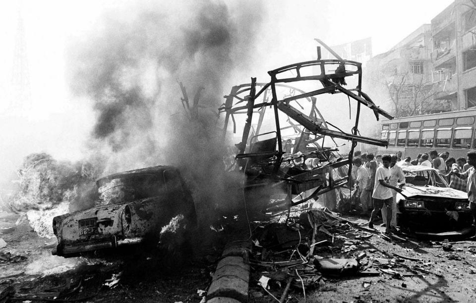 FILE - The skeletal remains of a transport bus are seen alongside burning vehicles and damaged buildings outside Bombay's Passport Office after a massive explosion, March 12, 1993. Twelve bombs exploded in less than 20 minutes at various locations, killing hundreds in India's financial capital. According to the Bombay Police, the prime culprit Dawood Ibrahim, who masterminded the attacks, is still at large and lives as a "free man" in Karachi, Pakistan. (AP Photo/Sherwin Crasto, File)