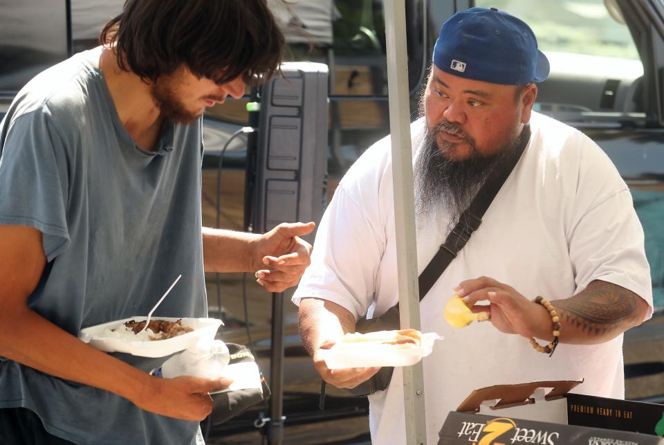 The Island Hut's Bailey Tupai offers up a banana to go along with their meal to a person living on MLK Way in Bremerton on July 31.