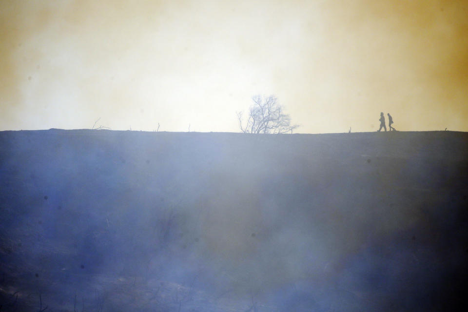 Firefighters walk on top of a burned down canyon caused by the Getty fire on Mandeville Canyon Monday, Oct. 28, 2019, in Los Angeles. (AP Photo/Marcio Jose Sanchez)