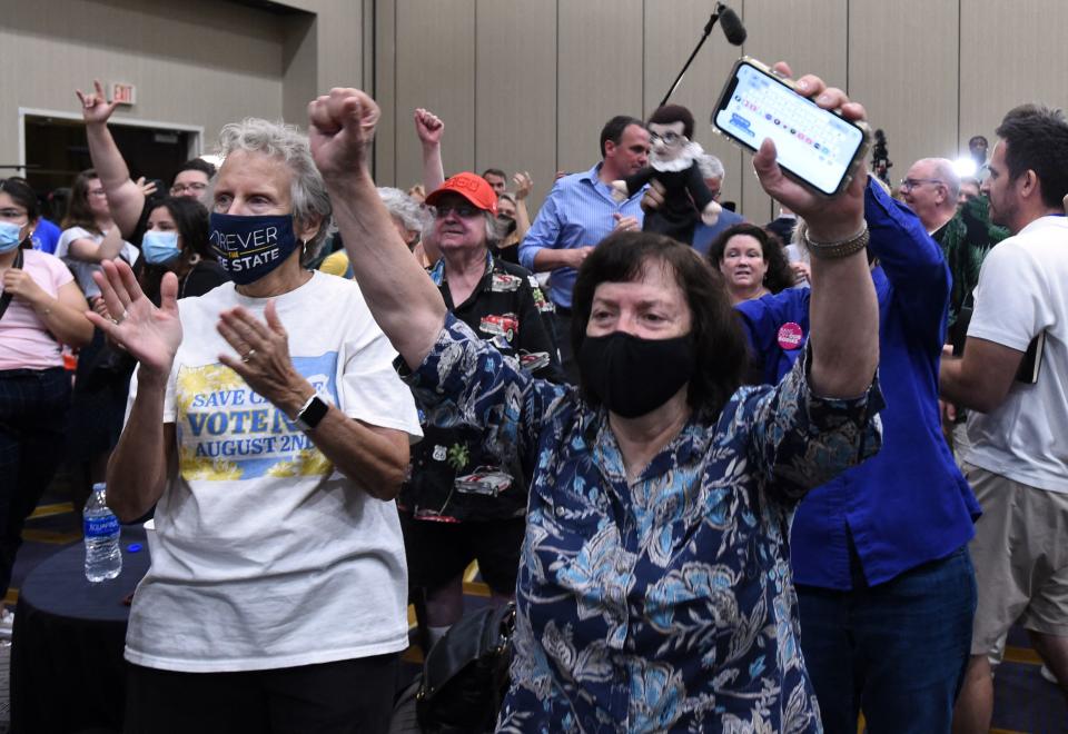 A group of women, mainly past middle age, cheer and raise their hands in the air.