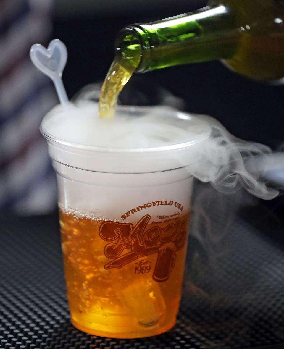 A bartender pours a Flaming Moe, a grape and orange-flavored drink with an optional shot of vodka at Moe's pop-up bar inside Missing Falls Brewery in Akron Friday.