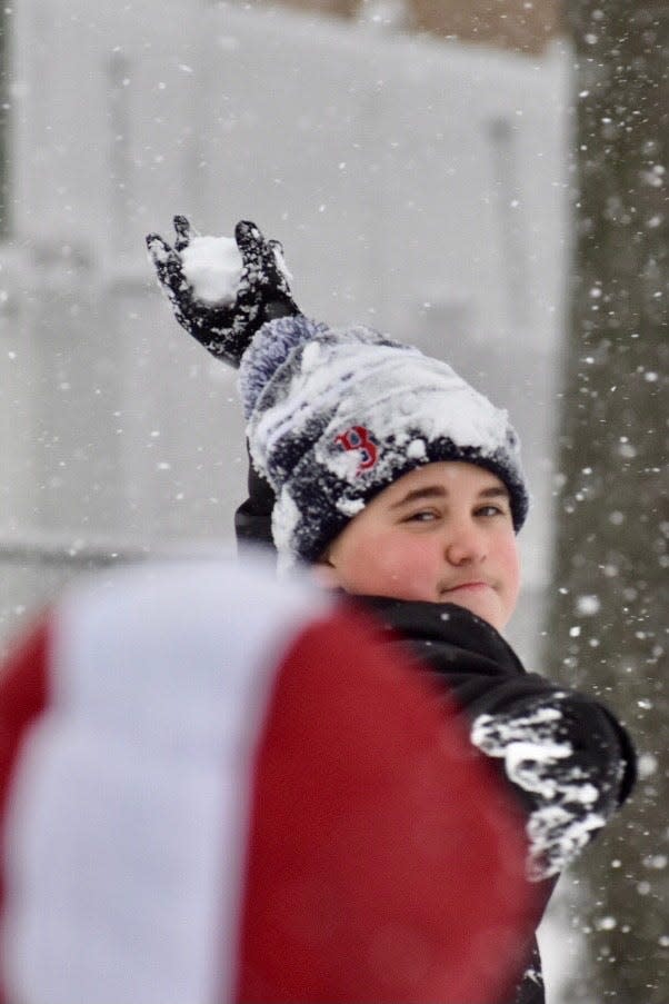 Jacob Farinha, 13, of Fall River, tosses a snowball to his brother, Brady, 12 on a school snow day Jan. 7, 2022.