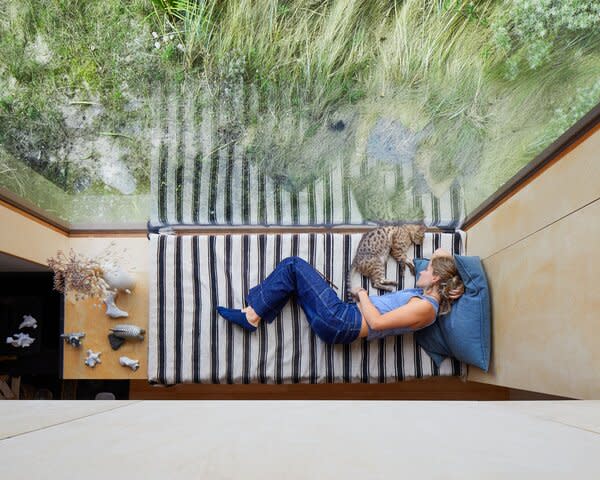Grass-covered dunes dot the coast of Cayeux-sur-Mer, a rugged resort town in northern France where filmmaker Olivier Panchot and business consultant Marie Becker built their holiday home. A striped daybed in the living area  provides a cozy perch for the couple’s teenage daughter, Lou, and the family’s Bengal cat, Kimiko.
