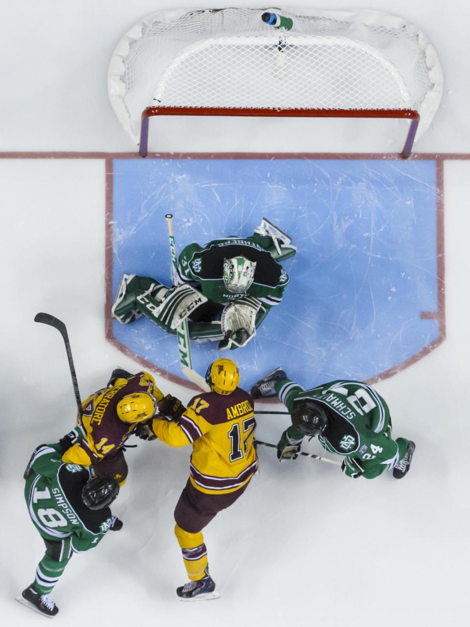 North Dakota's Zane Gothberg, top, looks to catch the puck with his glove as Minnesota's Tom Serratore, center left, and Seth Ambroz, center right, look for a rebound with North Dakota's Dillon Simpson, left, and Jordan Schmaltz, right, defending during the second period of an NCAA men's college hockey Frozen Four tournament game on Thursday, April 10, 2014, in Philadelphia. (AP Photo/Chris Szagola)