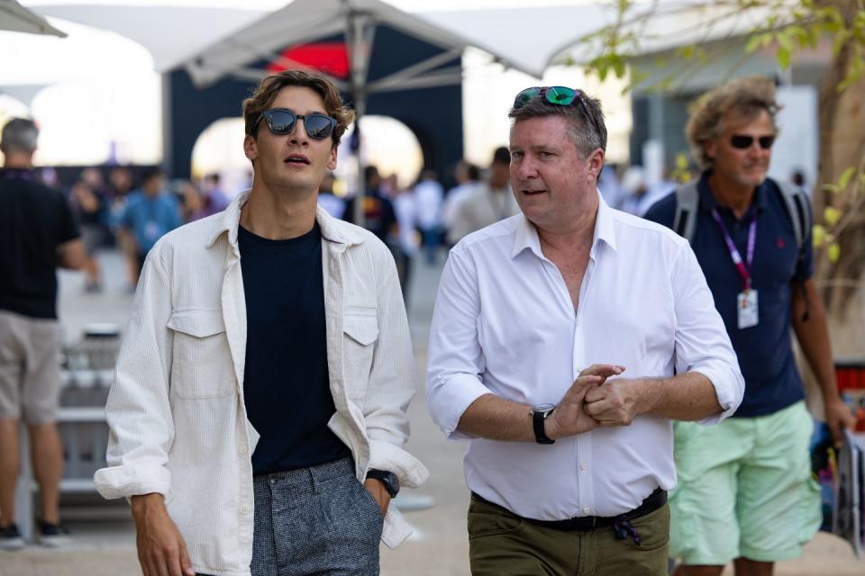 formula 1 driver george russell and commentator david croft walk in the paddock at a grand prix