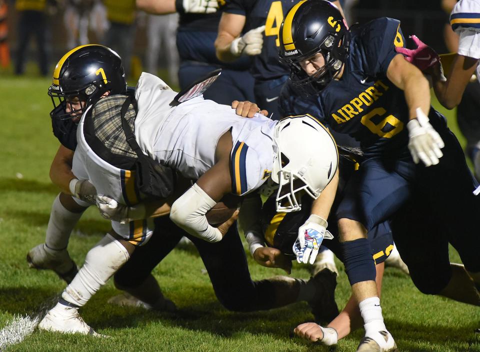 Jack Mills and Nolan Zajac of Airport bring down Rayshawn Kirk of Detroit East English during a 70-18 Airport rout in a Division 4 playoff game on Friday, October 27, 2023.