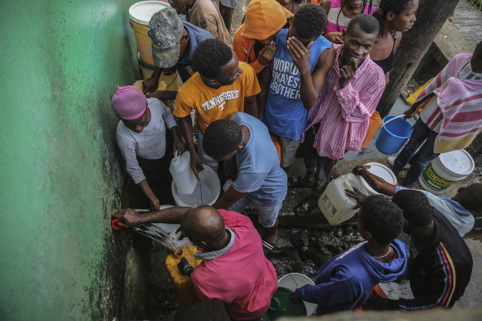 People displaced by Saturday´s 7.2 magnitude earthquake collect water after sleeping in the streets in Les Cayes, Haiti, Sunday, Aug. 15, 2021. (AP Photo/Joseph Odelyn)