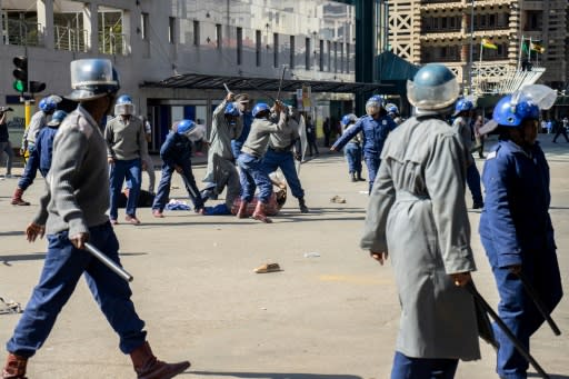 Police beat a protester in a public square in Zimbabwe's capital Harare