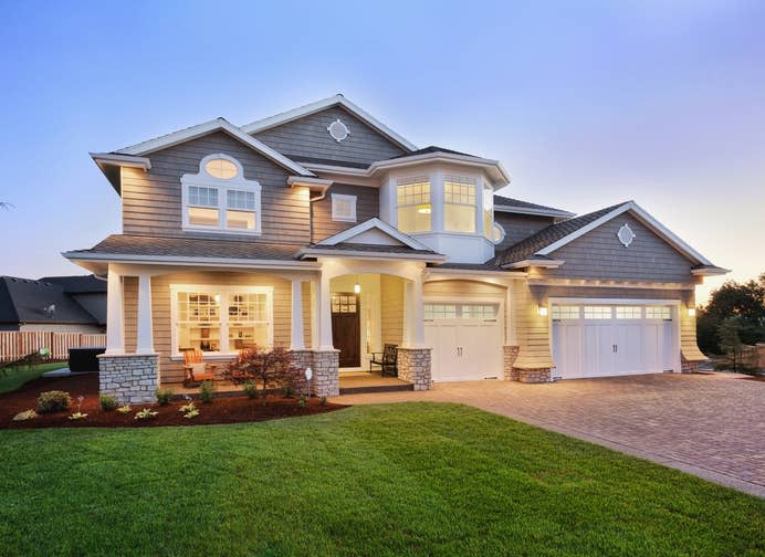 A modern, two-story suburban house with large windows, a well-manicured lawn, and an attached garage