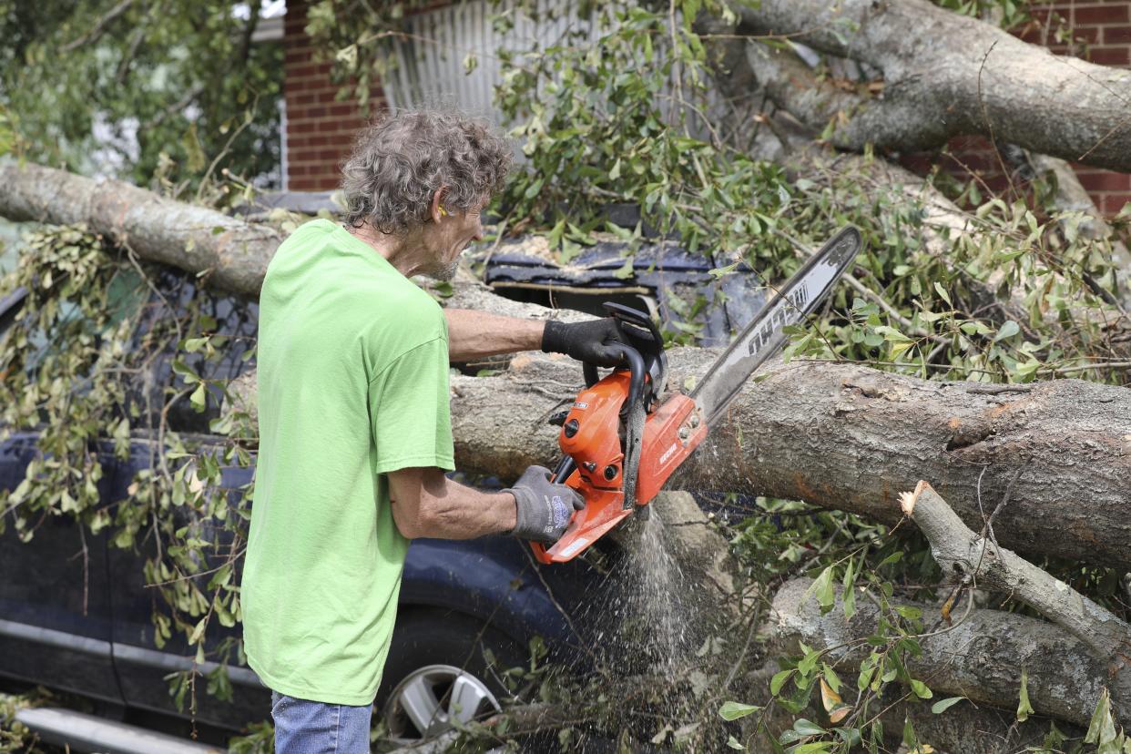 Andy Brown uses a chain saw to cut apart a tree that destroyed his SUV when it fell during Hurricane Helene on in Augusta, Ga., Tuesday, Oct. 1, 2024. (AP Photo/Jeffrey Collins)